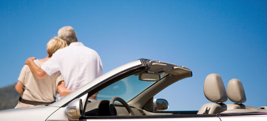 pareja mayor apoyada en un coche