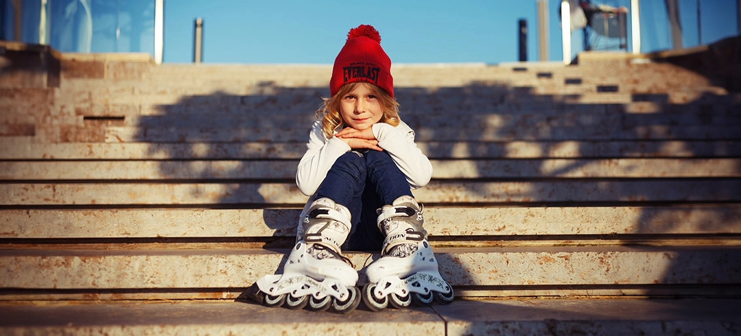 Niño sentado en unas escaleras con patines puestos en sus pies