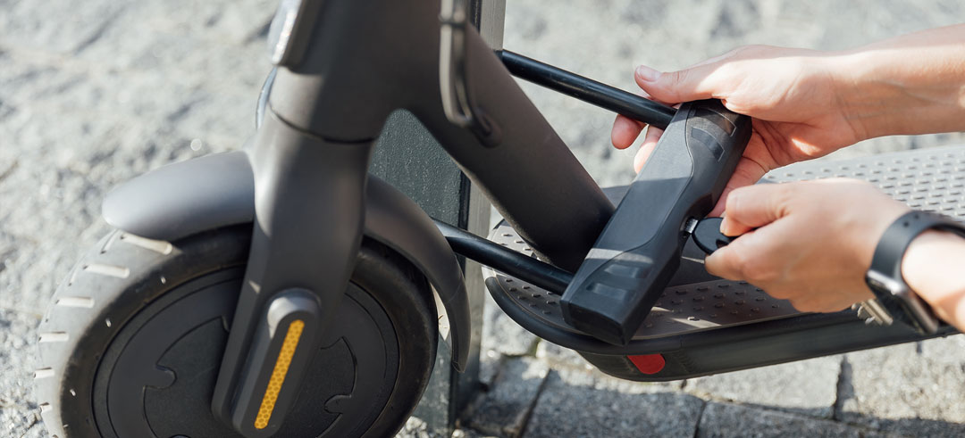 Persona poniendo un candado con llave en el patinete eléctrico