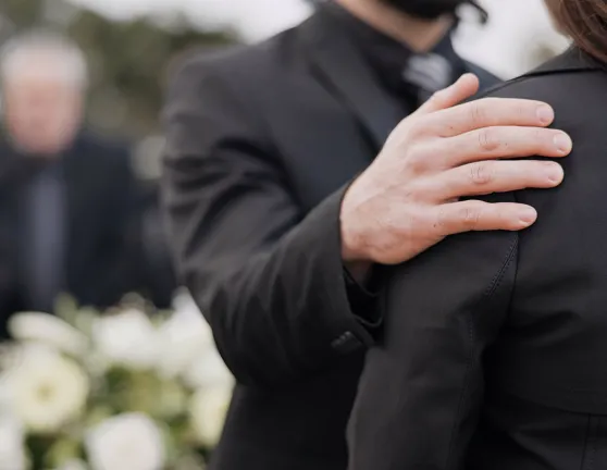 Una persona apoyando a otra en un funeral