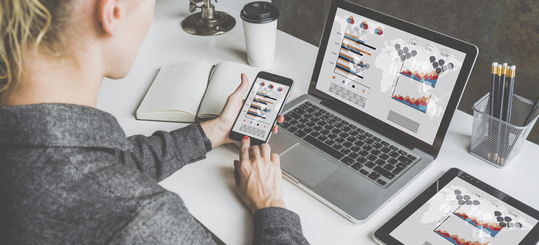 Persona viendo los mismo datos en un ordenador, móvil y tablet