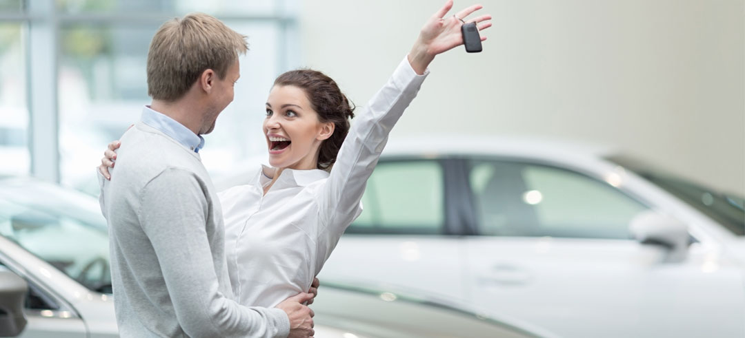 Pareja celebrando la compra de un coche en el concesionario
