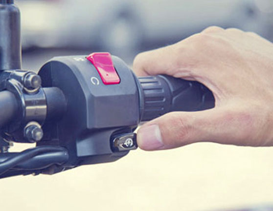 Persona arrancando una moto pulsando el botón de encendido